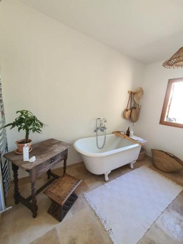 La salle de bains est pourvue d'une baignoire et d'une table avec une plante. dans l'établissement La Bergerie Pool and View, à Roquebrune-Cap-Martin