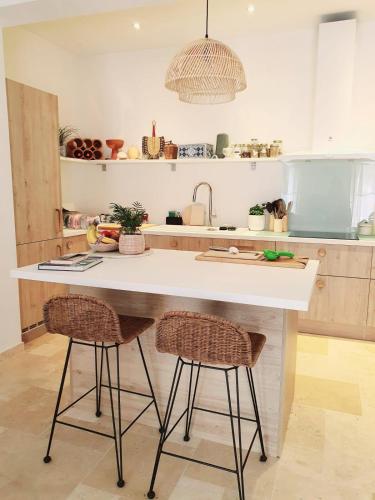 une cuisine avec un comptoir blanc et deux tabourets de bar dans l'établissement La Bergerie Pool and View, à Roquebrune-Cap-Martin