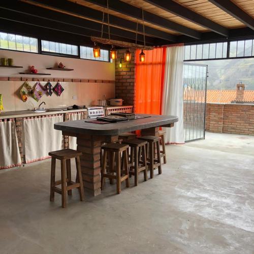 a large kitchen with a large table and stools at Posada María E in Mucuchíes