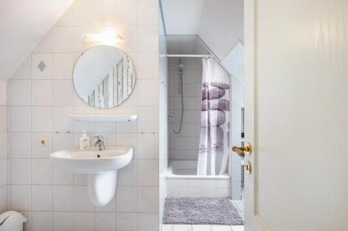 a bathroom with a sink and a mirror and a shower at Gästehaus Bi de Ley in Langeneß