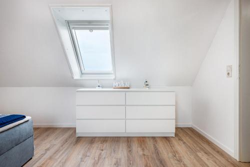 a white bathroom with a sink and a window at Gästehaus Bi de Ley in Langeneß