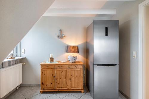 a kitchen with a refrigerator and a wooden cabinet at Gästehaus Bi de Ley in Langeneß