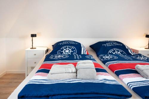 a bed with blue and white blankets and towels at Gästehaus Bi de Ley in Langeneß