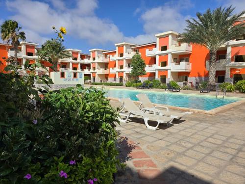 a swimming pool with two lounge chairs and some apartments at Paraiso Tropical wifi and pool Djadsal moradias in Santa Maria