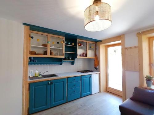 une cuisine avec des placards bleus et une lampe pendant dans l'établissement Au petit Névé, aux Houches