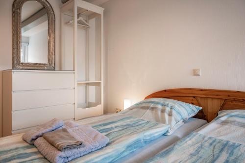 a bedroom with a bed and a mirror on the wall at Gästehaus Bi de Ley in Langeneß