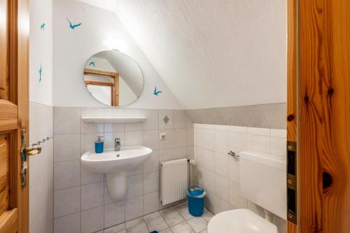 a bathroom with a sink and a toilet and a mirror at Gästehaus Bi de Ley in Langeneß