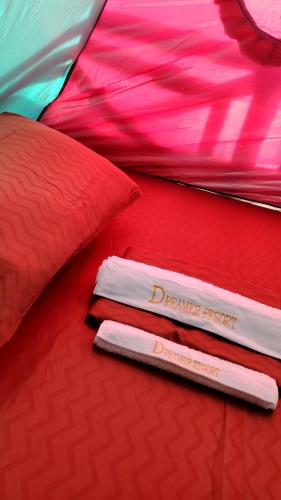 a red bed with two folded towels on it at Dreamer Resort in San Vicente
