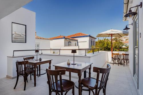 a patio with tables and chairs on a balcony at Maison Muse in Hydra