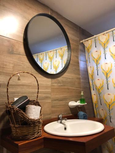 a bathroom with a sink and a mirror and a basket at Los ciruelos - Casas de Motaña in Tafí del Valle