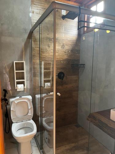 a bathroom with a toilet and a glass shower at Pousada do Altar in Conceição do Mato Dentro