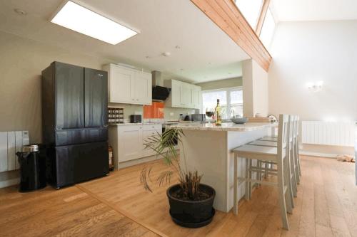 a kitchen with a black refrigerator and a table at Carew in the heart of Bantham with panoramic sea views in Bantham