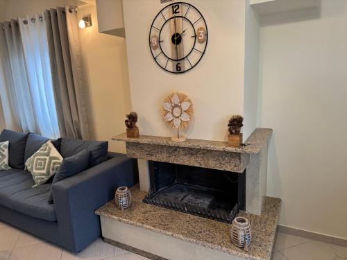 a living room with a blue couch and a clock on the wall at Eriand Maisonette in Lefkada Town