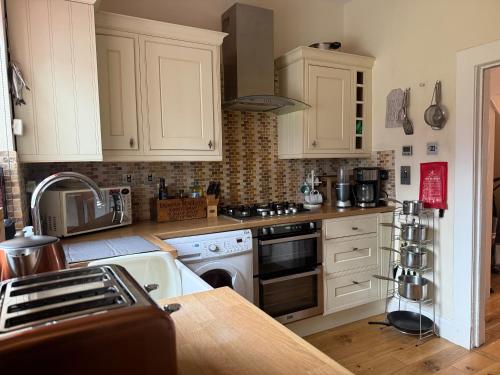a kitchen with white cabinets and a stove top oven at Riverside Cottage City Centre in Inverness