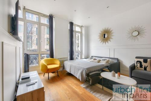 une chambre avec un lit, une chaise et une table dans l'établissement Urban Flat 34 - Beautiful 3 Bedroom Paris Louvre, à Paris