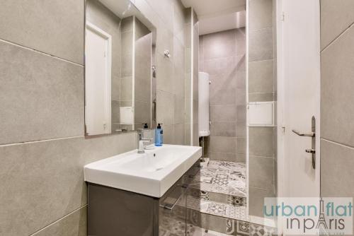 une salle de bain avec un lavabo blanc et une douche dans l'établissement Urban Flat 34 - Beautiful 3 Bedroom Paris Louvre, à Paris