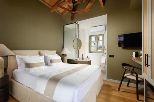 a bedroom with a large white bed and a mirror at Maison Muse in Hydra