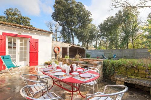 - une table et des chaises rouges sur la terrasse dans l'établissement Maison Serapias - Welkeys, à Dolus-d'Oléron