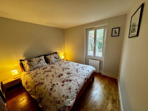 a bedroom with a bed with a floral bedspread and a window at Petite maison Normande Calme Meublé Tourisme 2 étoiles in Agon Coutainville