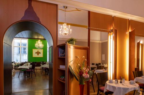 a dining room with tables and chairs and a chandelier at Pertschy Palais Hotel in Vienna