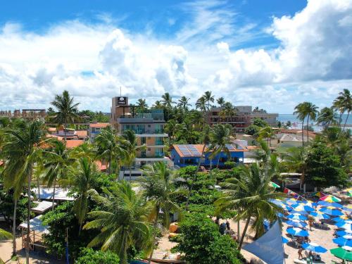 a view of a resort with palm trees and umbrellas at Tekatetu Hotels e Flats - Makadamia Porto de Galinhas in Porto De Galinhas