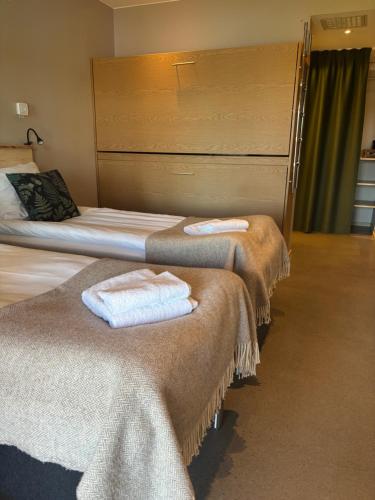two beds in a hotel room with towels on them at Åkulla Outdoor Resort in Rolfstorp