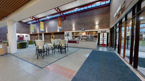 a lobby with chairs and tables in a building at Yarnfield Park Training And Conference Centre in Stone