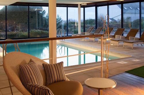 um átrio do hotel com cadeiras e uma piscina em Hostellerie de la Pointe Saint-Mathieu - SPA & Restaurant em Plougonvelin