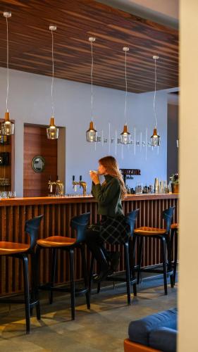 a woman sitting at a bar at Klosterhof – Alpine Hideaway & Spa in Bad Reichenhall