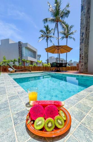 a tray of fruit and juice next to a swimming pool at Naluum Residence - Paraíso Pé na Areia em Milagres com Conforto e Lazer! in Passo de Camarajibe