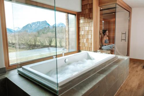 a large bath tub in a bathroom with a window at Klosterhof – Alpine Hideaway & Spa in Bad Reichenhall