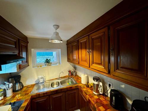 une cuisine avec des armoires en bois et un évier dans l'établissement Petite maison Normande Calme Meublé Tourisme 2 étoiles, à Agon-Coutainville