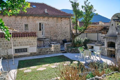 a backyard with a stone house with a table and chairs at Waterfront Historical Villa Perast in Perast