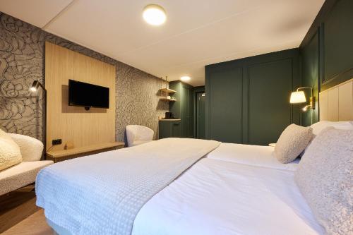 a bedroom with a large white bed and a tv at Hotel 't Kruisselt in De Lutte