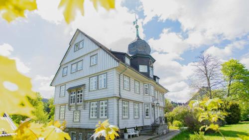 a large white house with a tower on top of it at Altes Rathaus Hahnenklee in Hahnenklee-Bockswiese