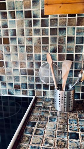 - un comptoir de cuisine avec des ustensiles en bois dans un seau métallique dans l'établissement Le domaine de Kerousy, à Plouguiel
