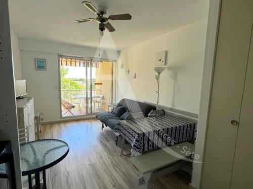un salon avec un canapé et un ventilateur de plafond dans l'établissement LES GRANGETTES, 4 pers, terrasse et parking, à Sète