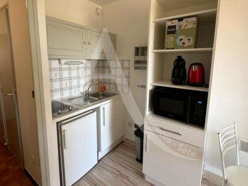 une petite cuisine avec un évier et un micro-ondes dans l'établissement LES GRANGETTES, 4 pers, terrasse et parking, à Sète
