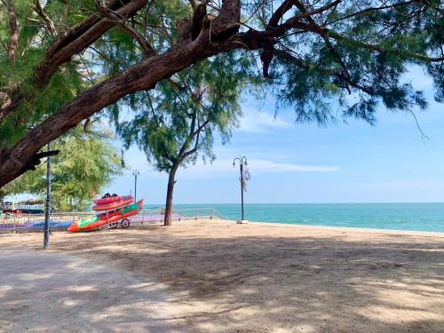 a red boat on the beach next to the ocean at Brown House Cha am in Cha Am