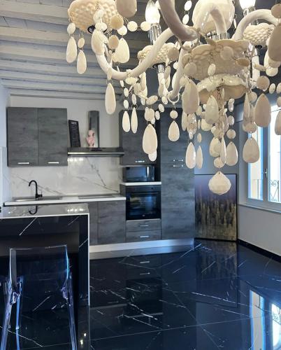 a kitchen with a chandelier and a black floor at URBAN JUNGLE TORTELLINOSUITE Modena in Modena
