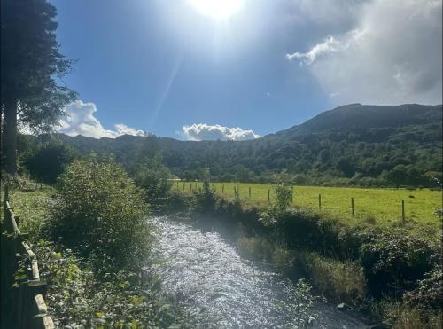 a river in a field next to a fence at Bridge House Hotel & Silver Howe View Cottage in Grasmere