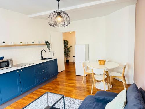 une cuisine et une salle à manger avec des armoires bleues et une table dans l'établissement Le Charme de Champagne - Proche Centre - Spacieux 3 chambres, à Troyes