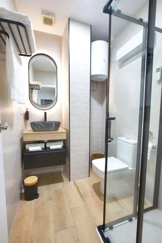 a bathroom with a sink and a toilet and a mirror at Cuencaloft el Rincón especial de Cuenca in Cuenca