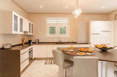 a kitchen with a table and chairs in a kitchen at Villa Aquaterra 200m2 - jacuzzi privatif chambre parentale, piscine, garage in Matoury