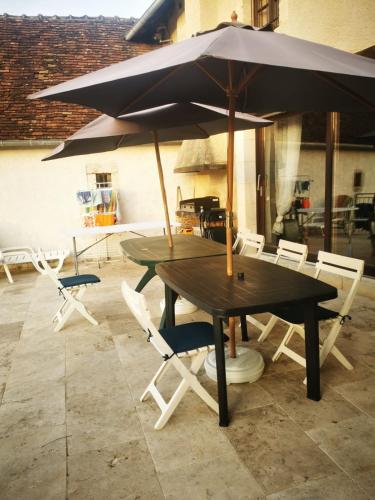 a wooden table with chairs and an umbrella at La Bastide des Chézeaux - Brenne in Rivarennes