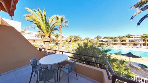 a balcony with a table and chairs and a swimming pool at Residencial Las Dunas, Best Holiday Home Resort On The Island- VV in Corralejo