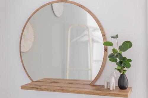 a mirror on a wooden shelf with a plant at Troja Living Helena - Wohnung zentral in Bruchsal in Bruchsal