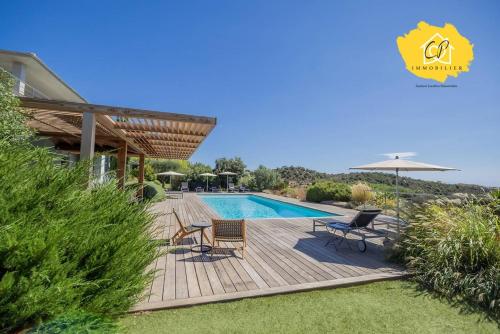une piscine avec des chaises et un parasol à côté d'une maison dans l'établissement Villa d’exception 4 chambres, piscine, vue mer, à Porto-Vecchio