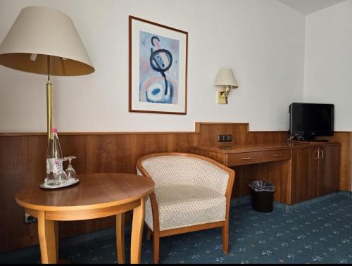 Habitación con mesa, silla y lámpara. en Pension De Lux Augsburg, en Augsburg