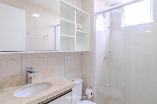a white bathroom with a sink and a shower at Prédio com piscina a 400m da Praia - LEA in Piçarras